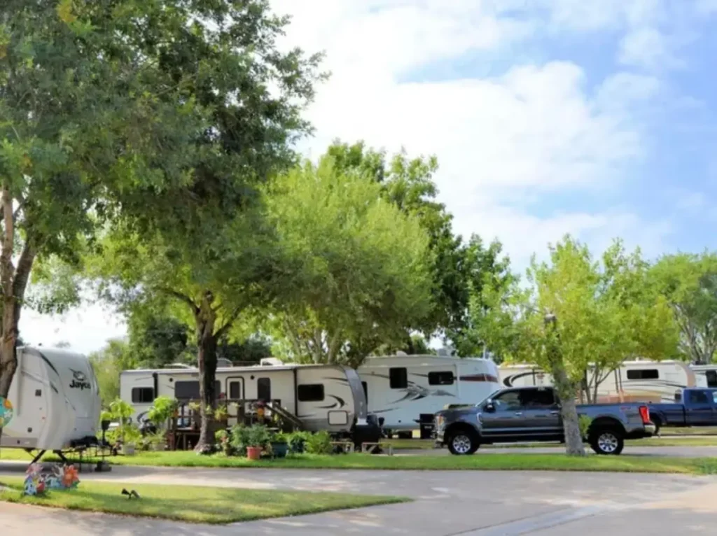 A view of Dad's RV Park with RVs parked among trees on a sunny day.