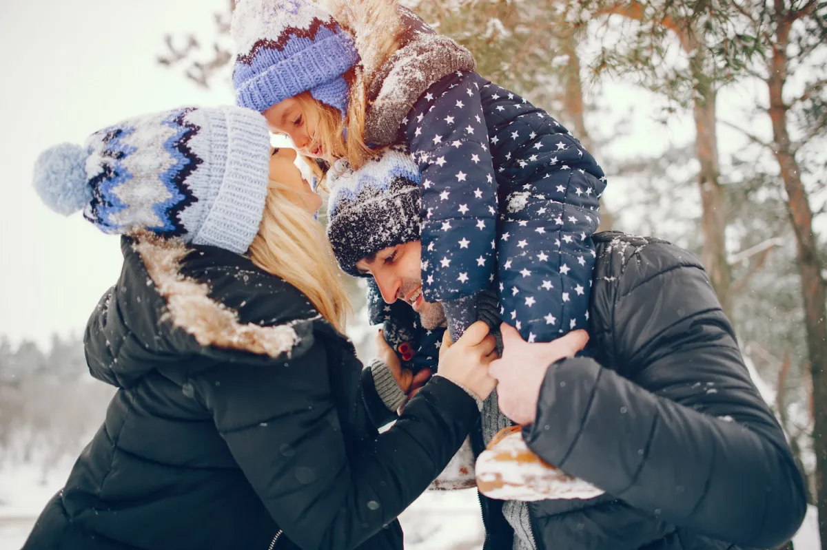 Parents lifting child during snowy play