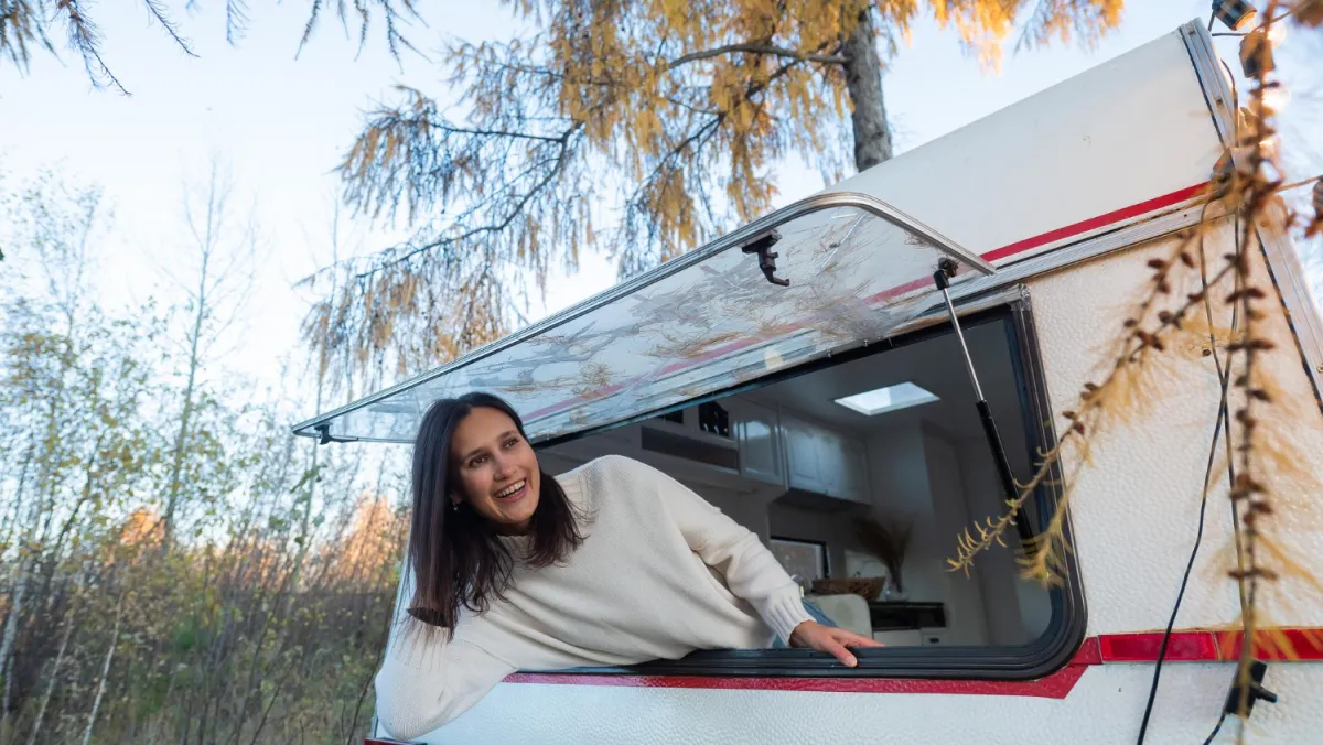 Woman leaning from camper window outdoors